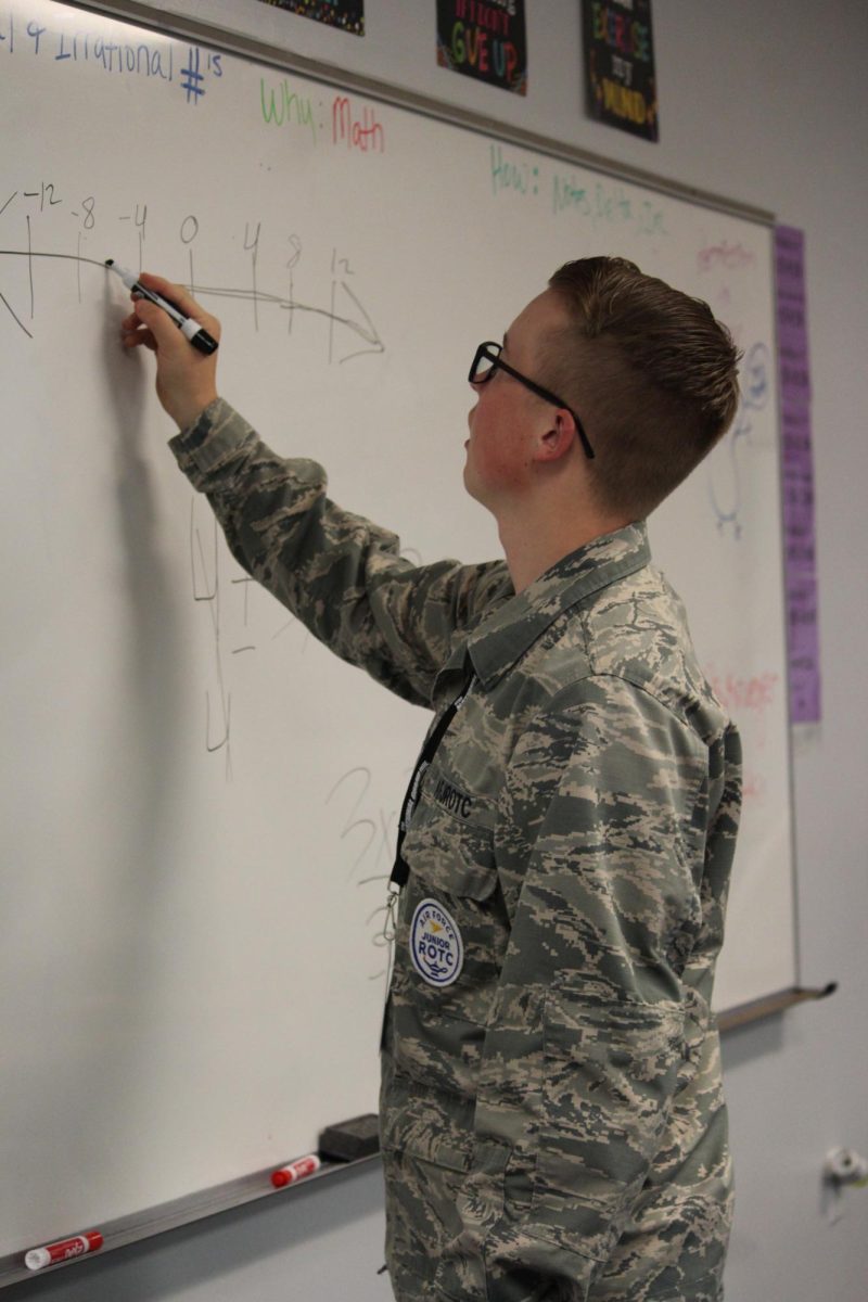 A cadet writes an equation on the board.