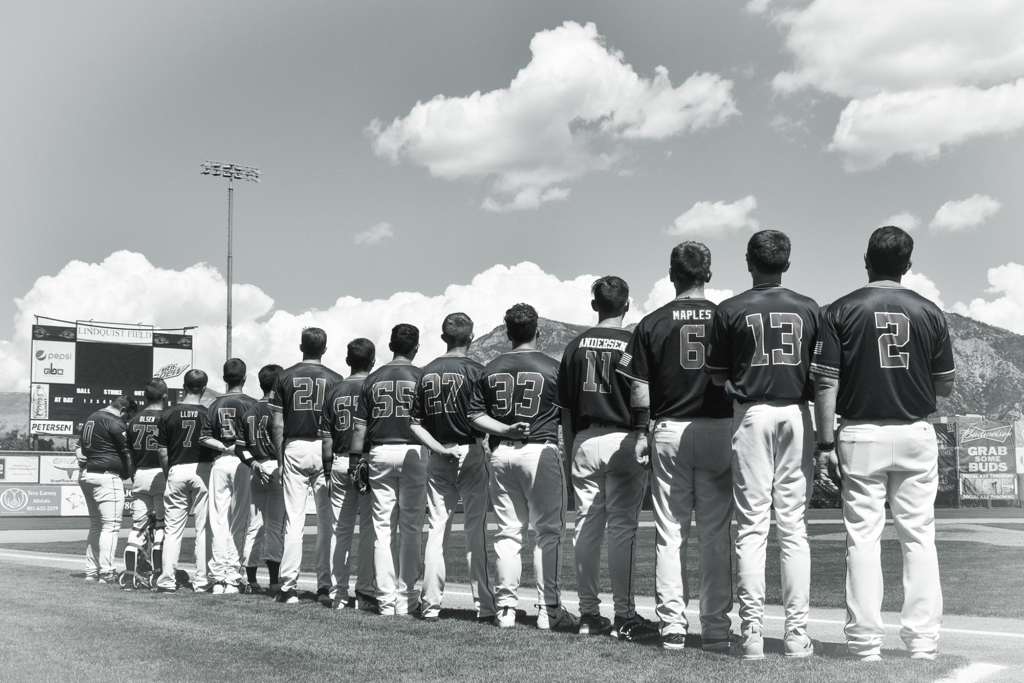 The Baseball team lines up for the National Anthem.